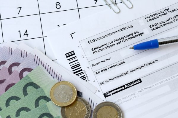 German tax form with pen and european money bills lies on office calendar